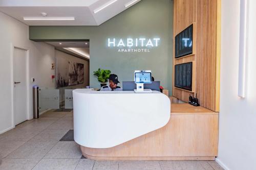 Habitat Aparthotel by Totalstay في كيب تاون: رجل يجلس في مكتب الاستقبال في مكتب