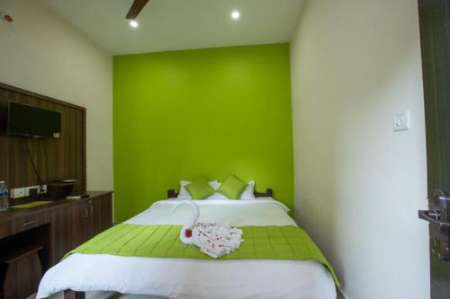 a bedroom with a green wall and a bed at Paradise Auro Resort in Kottakupam
