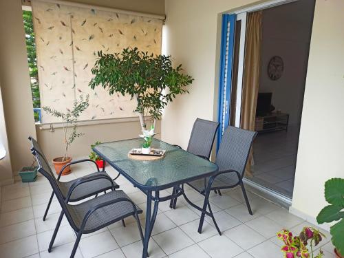 a table and chairs on a porch with a potted plant at Nefeli's Home- Family luxury apartment in Heraklio Town