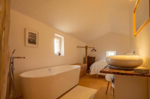 une salle de bain avec une baignoire blanche et un lavabo dans l'établissement Le Petit Mas, à Belvézet