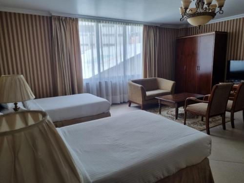 a hotel room with two beds and a chair at The Residence Hotel in Addis Ababa