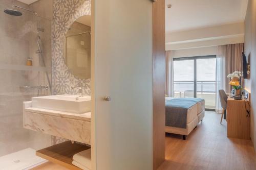 a bathroom with a sink and a bed and a mirror at Sentido Galosol in Caniço