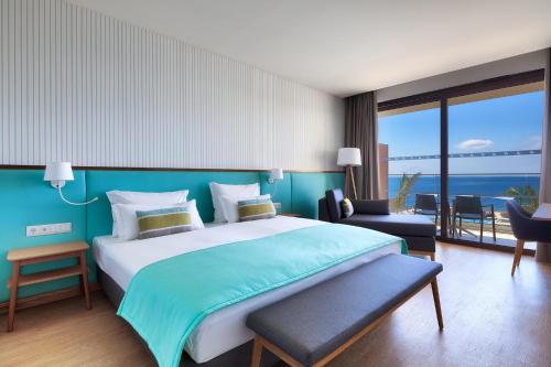 a bedroom with a large bed with a blue wall at Sentido Galomar - Adults Only in Caniço