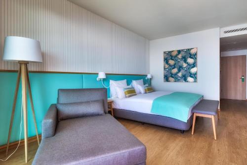 een slaapkamer met een bed, een stoel en een bank bij Sentido Galomar - Adults Only in Caniço