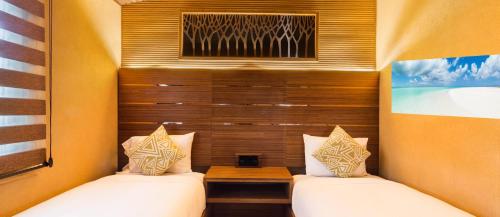 two beds in a small room with a window at Kokomo Botanical Resort - Caribbean Family Cottages in Turtle Cove