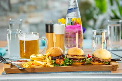 a tray with two burgers and fries and two glasses of beer at Kokomo Botanical Resort - Caribbean Family Cottages in Turtle Cove