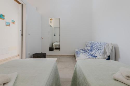 a white room with two beds and a mirror at Villa Torre Guaceto by Typney in Carovigno
