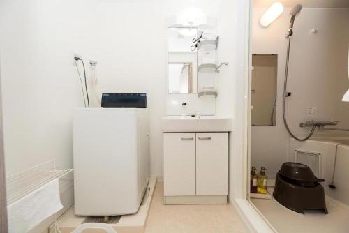 Baño blanco con lavabo y espejo en Voga Kolte Chidorimachi - Vacation STAY 7883, en Tokio