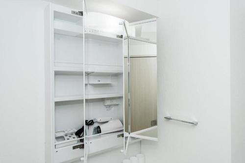 un armario blanco con estanterías blancas y una puerta de cristal en Voga Kolte Chidorimachi - Vacation STAY 7883, en Tokio