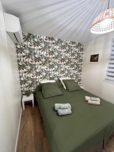 una camera da letto con un letto verde e asciugamani di l’Anita a Théoule-sur-Mer