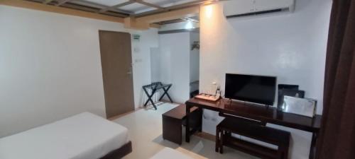 - une chambre avec un lit et un bureau avec une télévision dans l'établissement Regency Hotel de Vigan, à Ayusan Norte