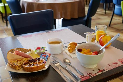 a table with a plate of breakfast food and a cup of coffee at BRIT HOTEL Confort CAMBRAI in Cambrai