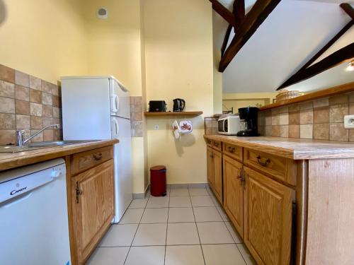 La cuisine est équipée d'un réfrigérateur blanc et de placards en bois. dans l'établissement Gîte Frossay, 3 pièces, 5 personnes - FR-1-306-1042, à Frossay