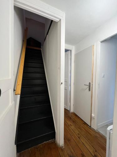 a staircase in an apartment with white walls and wooden floors at Gîte le charme citadin 55 m² avec extérieur in Valenciennes