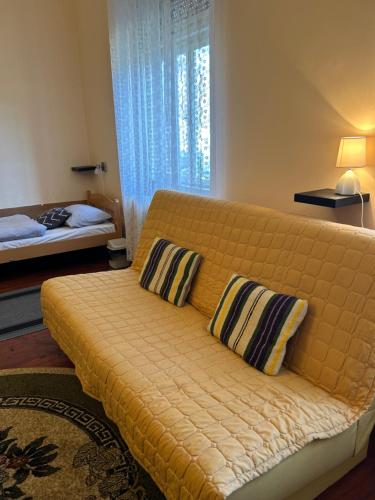 Sofá amarillo con 2 almohadas en una habitación en Guest House Anna Vendégház en Svetozar Miletić