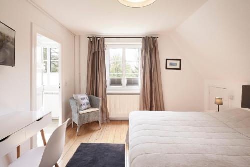 ein Schlafzimmer mit einem Bett, einem Stuhl und einem Fenster in der Unterkunft Haus Carolinenhöhe in Wyk auf Föhr