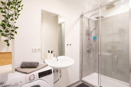 a white bathroom with a sink and a shower at Oktoberfest Oasis for up to 12 in Munich