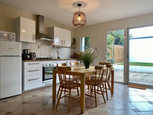 une cuisine avec une table et des chaises en bois ainsi qu'une salle à manger dans l'établissement Charmante Maison au Cœur d’un Village Paludier, Proche Guérande et Plages, Terrasse et Wifi - FR-1-306-1227, à Guérande