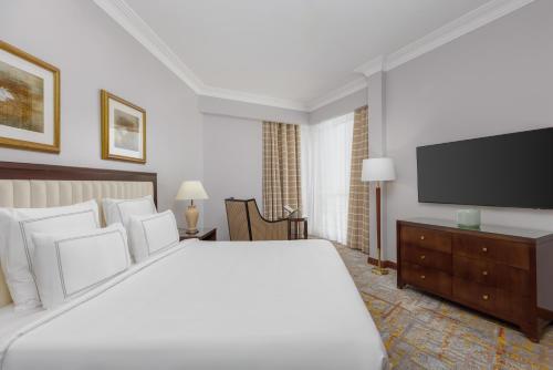 a bedroom with a large bed and a flat screen tv at Swissotel Al Maqam Makkah in Makkah