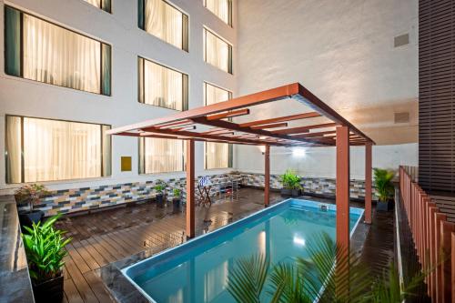偉傑瓦拉的住宿－Grand Vijayawada by GRT Hotels，一座带开放式遮阳伞的建筑中的游泳池