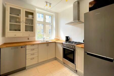 cocina con armarios blancos y nevera de acero inoxidable en 2 Bedroom Flat in Trendy Area en Copenhague