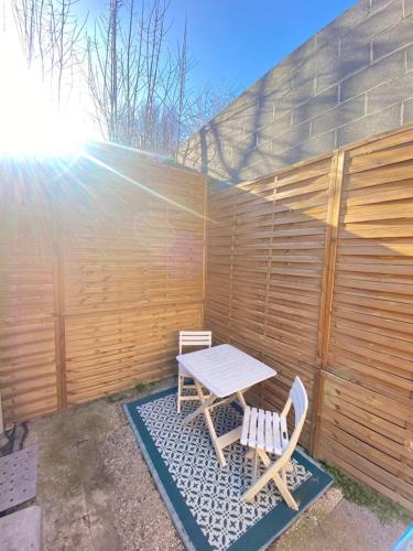 a picnic table and two chairs in front of a fence at Gîte le charme citadin 55 m² avec extérieur in Valenciennes
