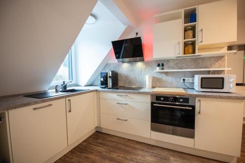 a kitchen with white cabinets and a sink and a microwave at Queensize Bett & Netflix zentral in Idar-Oberstein