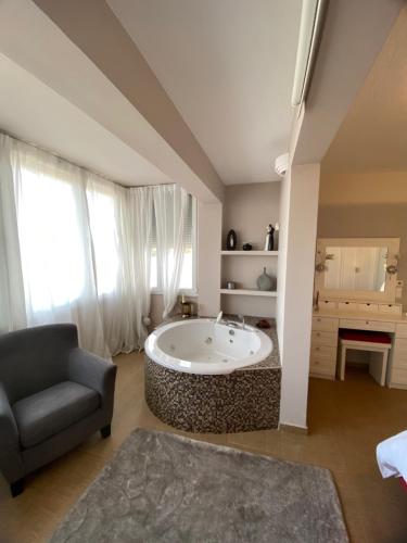 a large bathroom with a tub and a chair at Hillside View Villa in Thermi