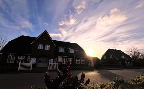 duas casas com o pôr do sol no céu em Hotel Anka em Norddorf