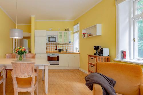 eine Küche mit gelben Wänden sowie einem Tisch und Stühlen in der Unterkunft Haus Friedrichsen 05 in Wyk auf Föhr