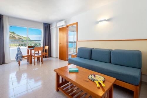 ein Wohnzimmer mit einem blauen Sofa und einem Tisch in der Unterkunft Apartamentos Vibra Tropical Garden in Ibiza-Stadt