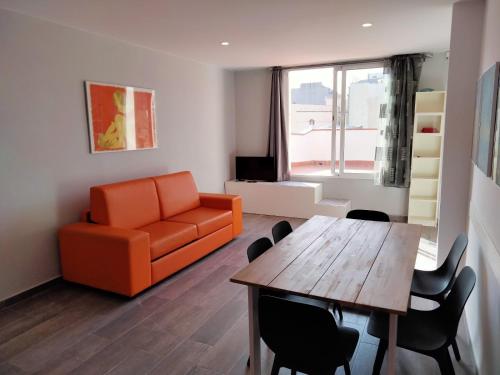 a living room with a table and an orange couch at Apartamentos Turísticos Tenor by Bossh! Hotels in Barcelona