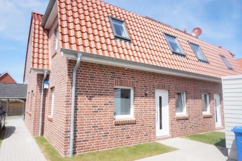 una casa de ladrillo con techo naranja en Doppelhaushälfte Nordseewind, en Carolinensiel