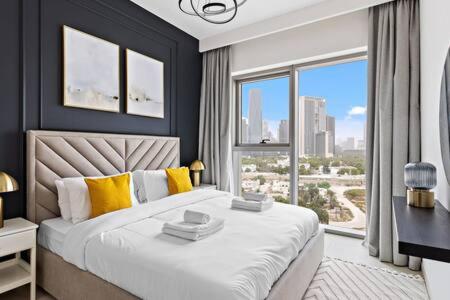 um quarto com uma cama grande e uma janela grande em Silkhaus luxurious 1BDR in new tower with pool & gym no Dubai