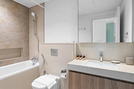 a bathroom with a sink and a toilet and a tub at Silkhaus luxurious 1BDR in new tower with pool & gym in Dubai