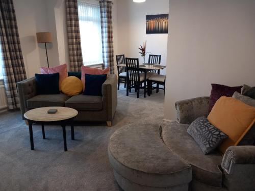 a living room with couches and a table and chairs at Springfield Apartment - Train to Glasgow or Edinburgh - Private Parking & Wifi in Airdrie