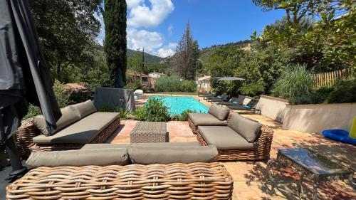 - une piscine avec 2 chaises longues et un canapé en osier dans l'établissement Bergerie à quelques minutes du centre de Grimaud, à Grimaud
