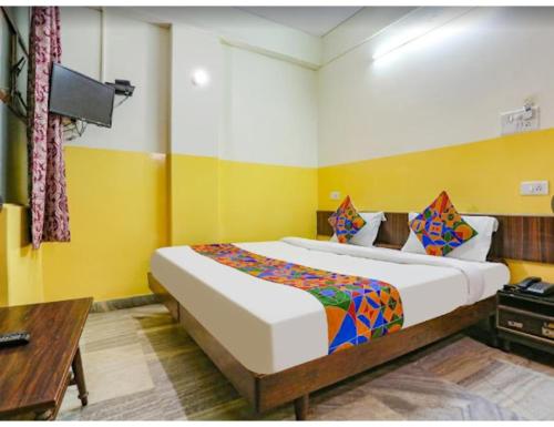 1 dormitorio con 1 cama grande en una habitación con paredes amarillas en Hotel Ashoka Inn, Kanpur, en Kānpur