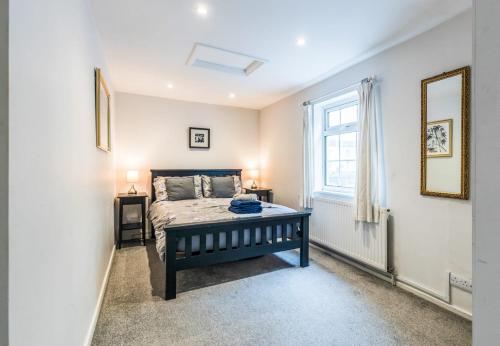 Schlafzimmer mit einem Bett und einem Fenster in der Unterkunft 1 Phoenix Cottages, 403 High Street, Cheltenham in Cheltenham