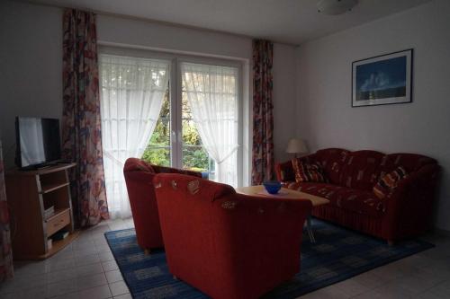 a living room with a red couch and a table at Ferienhaus Hylla Fischerstraße in Carolinensiel