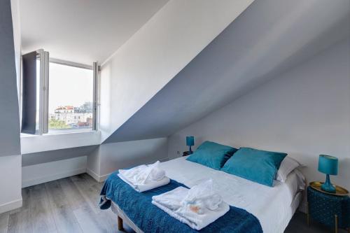 a bedroom with a bed with blue pillows and a window at 804 Suite Styling - Superbe Duplex in Bagnolet