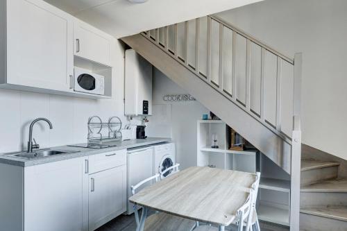 une cuisine avec des placards blancs et une table en bois dans l'établissement 804 Suite Styling - Superbe Duplex, à Bagnolet