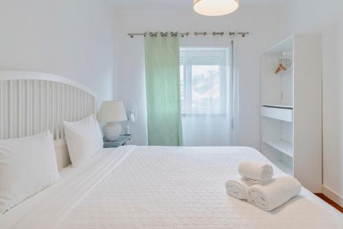 a white bedroom with two towels on a bed at Pátios das Marias - Rosas in Setúbal