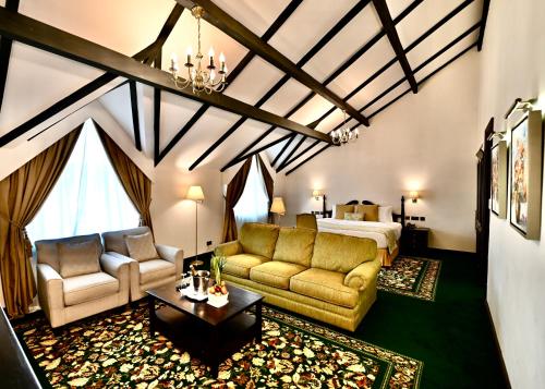 a room with a bed and a couch and a table at Midland Hotel Nakuru in Nakuru