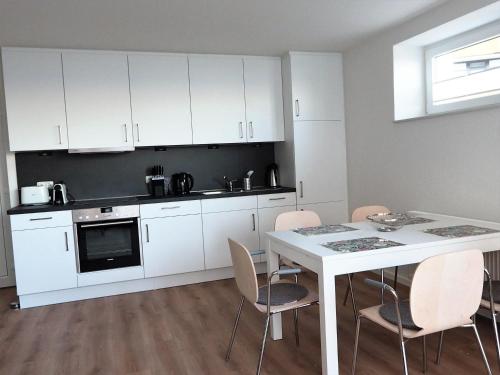 uma cozinha com armários brancos e uma mesa e cadeiras em FIS 001 - Seeperle em Scharbeutz