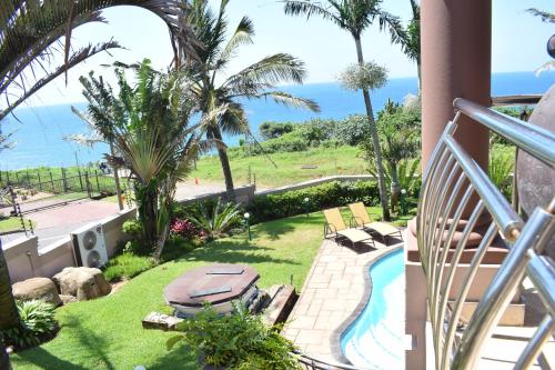 a balcony with a swimming pool and palm trees at 134 On Ocean View in Amanzimtoti