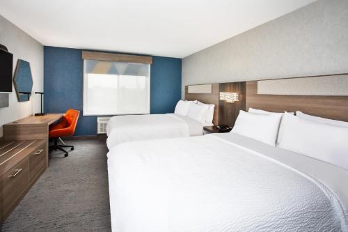 a hotel room with two beds and a desk at Holiday Inn Express Hotel & Suites - Belleville Area by IHG in Belleville