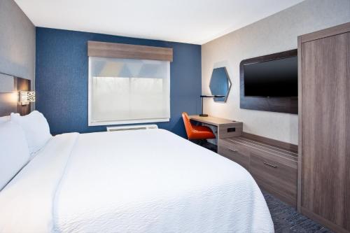 a hotel room with a bed and a flat screen tv at Holiday Inn Express Hotel & Suites - Belleville Area by IHG in Belleville