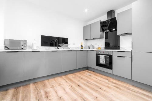 a kitchen with white cabinets and a wooden floor at Stylish Apartment - 2 Bedrooms - Balcony - Parking - Netflix - Wifi - 7MC in Birmingham