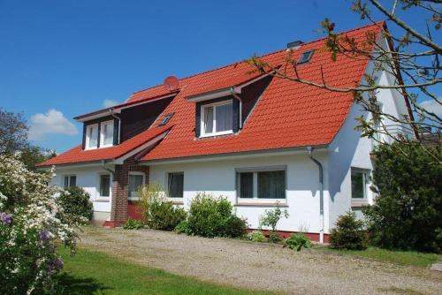 une maison blanche avec un toit orange dans l'établissement HAF OGa - Gästehaus Starke, à Haffkrug